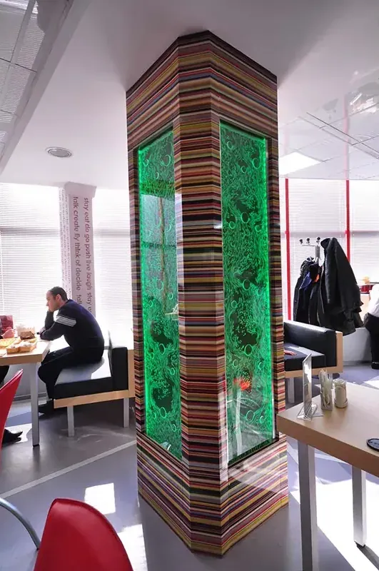 Green-lit bubble wall wrapping a structural column in a cafe