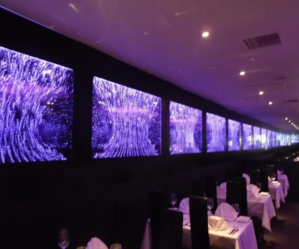 Row of purple-lit bubble-wall panels dividing a restaurant dining room