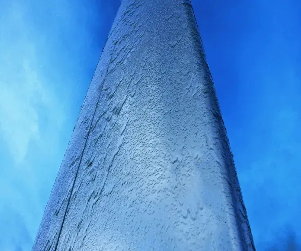 Looking up a curved stainless steel waterwall panel with water beading over its surface