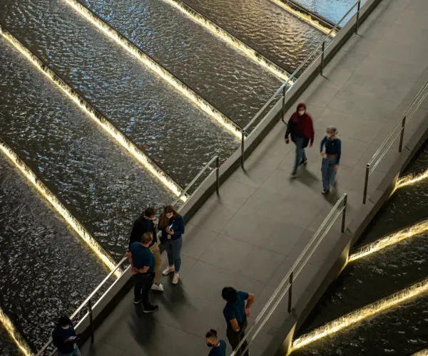 Illuminated water stairs stepping down a plaza walk