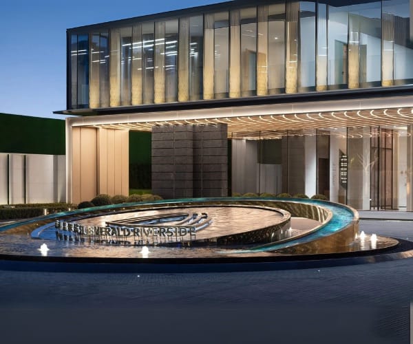 Round fountain with vertical jets in a modern building forecourt at dusk