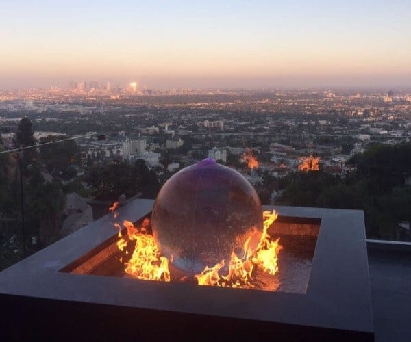 Spherical fire feature burning at dusk with the Los Angeles skyline behind