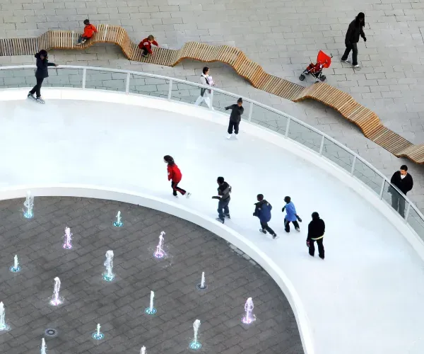 Families walking around a circular interactive fountain ring