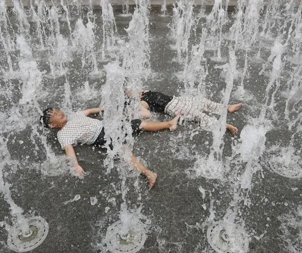 Children lying among the jets of an interactive splash pad, seen from above