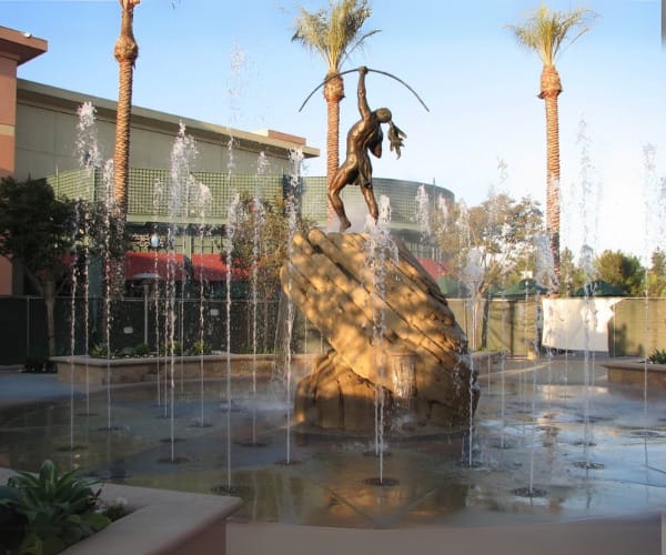 Bronze dancer sculpture over an interactive splash court lined with palms