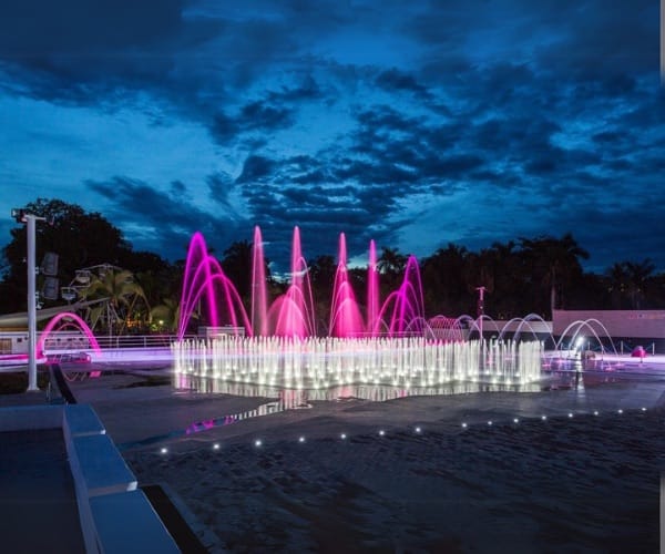 Magenta-lit fountain field on a plaza at dusk