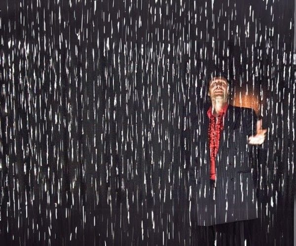 Figure standing inside a black digital rain curtain, water parting around him