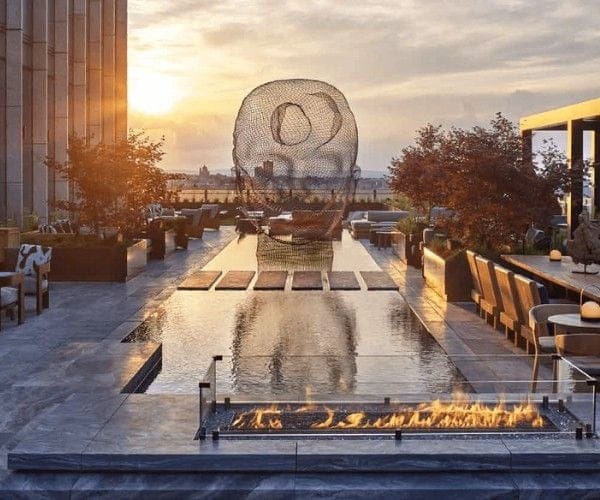 Woven wire sphere and fire feature over a rooftop reflecting pool at sunset