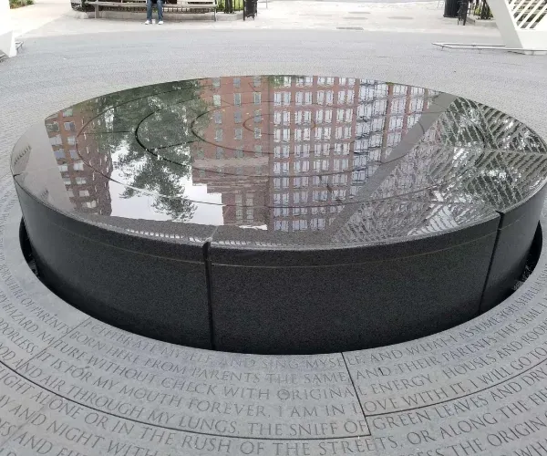 Circular black-granite reflection pool engraved with text at the NYC AIDS Memorial