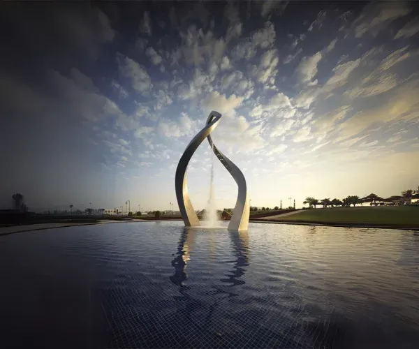 Wishbone-form sculpture rising from a horizon pool at dusk