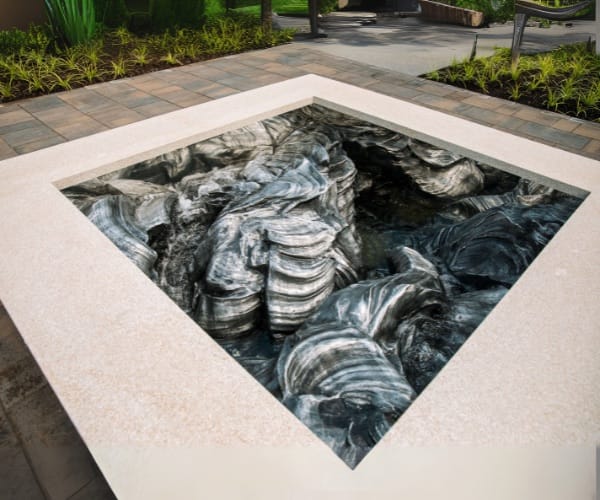 Carved sculptural forms set into a sunken stone-edged pool court