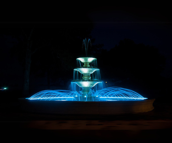 Blue-lit tiered fountain at night