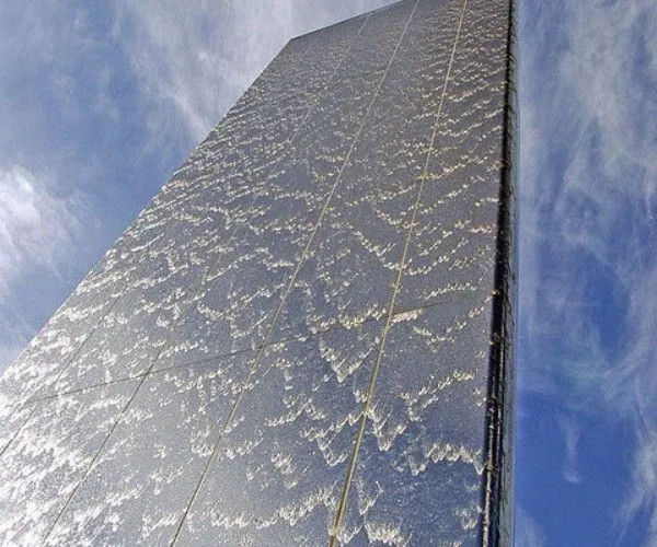 Monumental outdoor waterwall tower patterned with cascading water against a blue sky