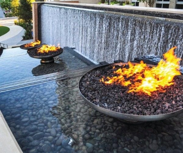 Fire bowls burning along the crest of a cascading waterfall