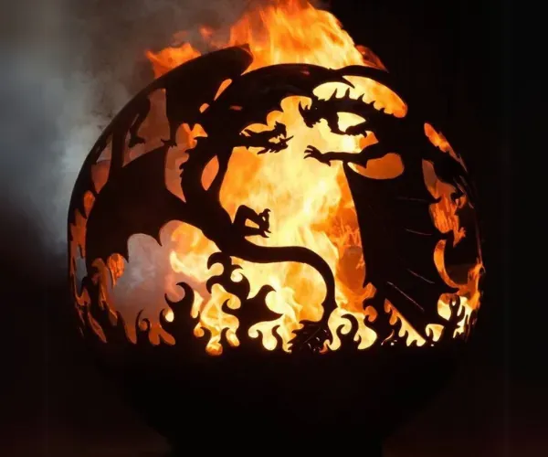 Plasma-cut steel fire sphere with dragon silhouettes, fully alight