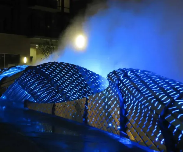 Blue-lit lattice form wrapped in architectural fog at night
