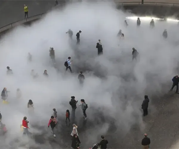 Overhead view of a crowd walking through a dense fog cloud on a plaza
