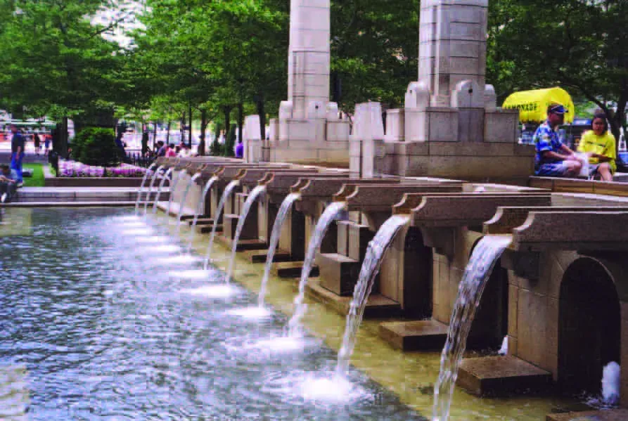 A row of arcing granite scuppers pouring into an urban plaza basin