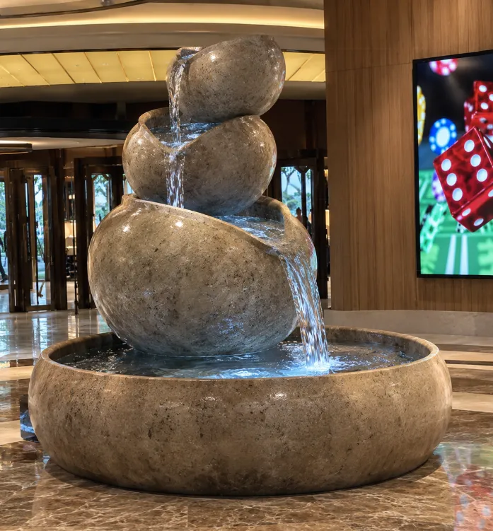 Stacked stone fountain with water spilling between rounded boulders