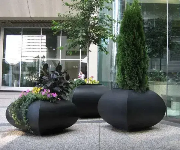 Black steel planters with seasonal planting on a city plaza