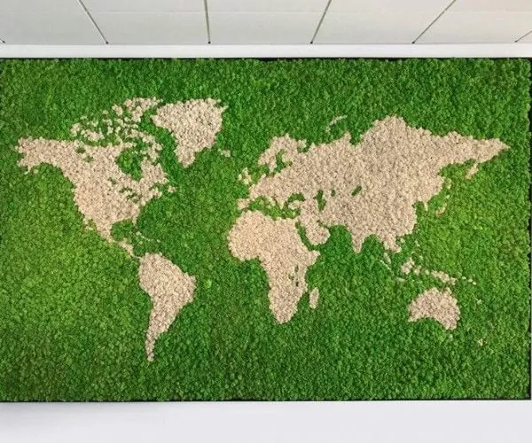 Moss world map with pale continents on deep green, mounted on a white wall