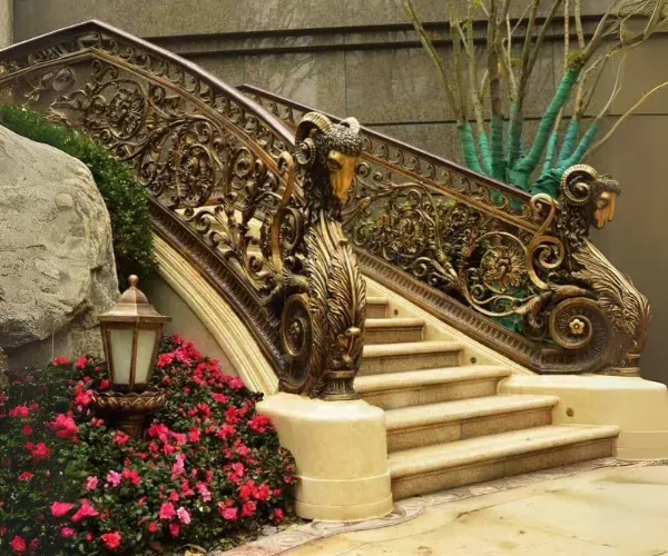 Ornate bronze stair railing with scrollwork on a garden staircase