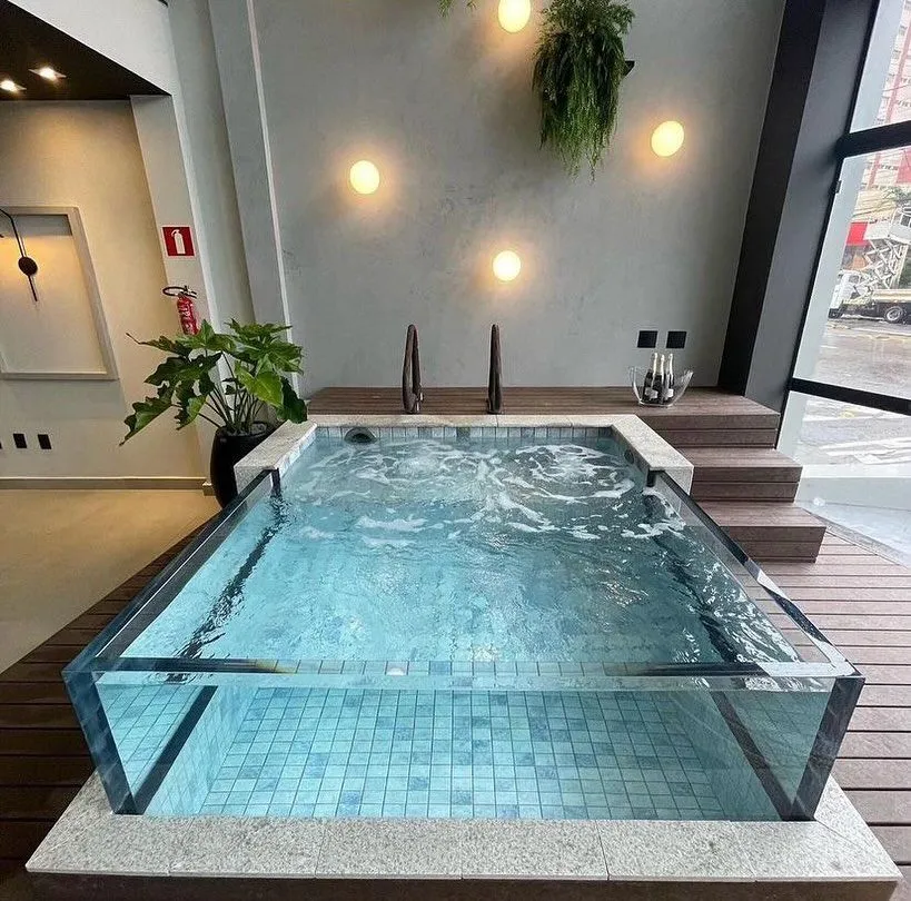 Spa with a clear acrylic front wall and bubbling jets in a tiled room