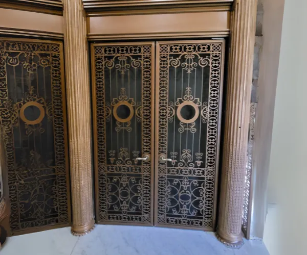 Pair of ornate filigree bronze doors between stone columns