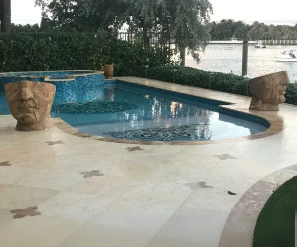 Carved stone heads set around a mosaic pool deck