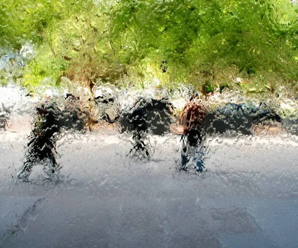 Water sheeting over mirror glass with blurred figures behind